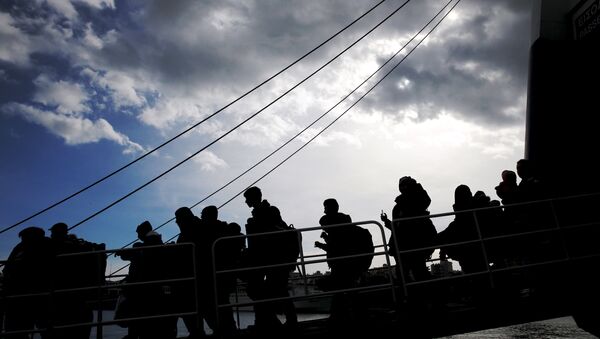 Refugees and migrants are silhouetted as they arrive aboard the passenger ferry Ariadne at the port of Piraeus, near Athens, Greece, January 4, 2016. - Sputnik International