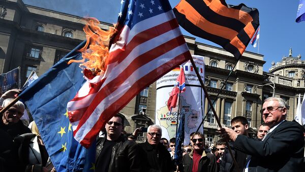 Serbian nationalist politician Vojislav Seselj (R) surrounded by his supporters holds a burning NATO flag during an anti-government rally on March 24, 2015, in front of the building of the former federal Interior Ministry in Belgrade - Sputnik International