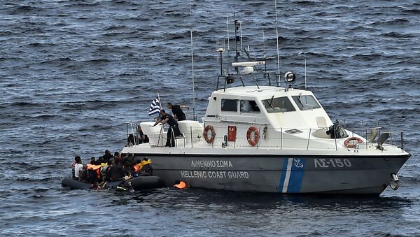 Hellenic coast guard personnel rescue refugees and migrants on a dinghy as they try to reach the Greek island of Lesbos while crossing the Aegean sea from Turkey on September 29, 2015 - Sputnik International