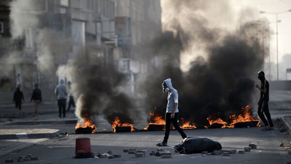 Bahraini protesters walk past burning tyres during clashes with riot police in the village of Sitra, south of the capital Manama, on January 8, 2016, following a protest against the execution of prominent Shiite Muslim cleric Nimr al-Nimr by Saudi authorities - Sputnik International