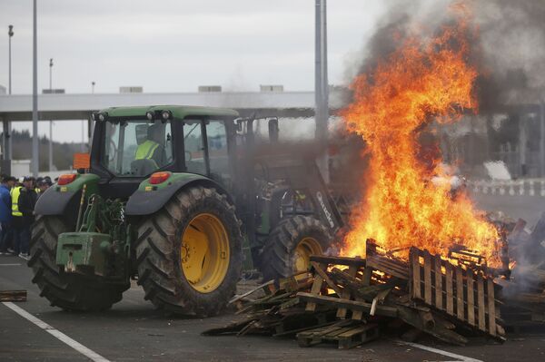 French livestock farmers gather near burning palettes to protest falling prices near at a toll booth on the autoroute in Ancenis, western France, January 27, 2016 French livestock farmers gather near burning palettes to protest falling prices near at a toll booth on the autoroute in Ancenis, western France, January 27, 2016 - Sputnik International