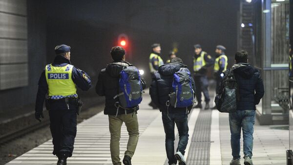 A police officer escorts migrants from a train at Hyllie station outside Malmo, Sweden. Picture taken November 19, 2015 - Sputnik International