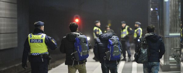 A police officer escorts migrants from a train at Hyllie station outside Malmo, Sweden. Picture taken November 19, 2015 - Sputnik International