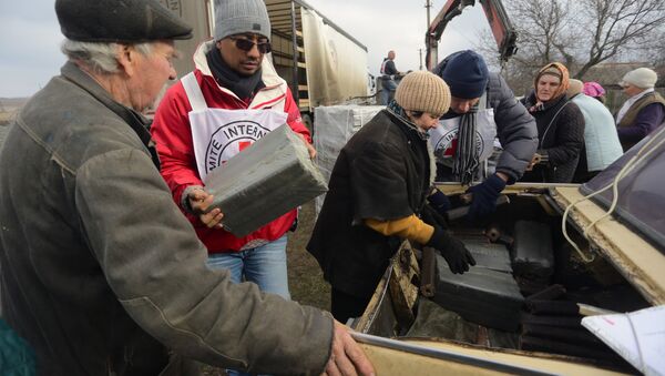 A picture taken on December 22, 2015 shows local residents receiving free wood briquettes delivered by the Red Cross in the village of Pischevik, in the Donetsk region - Sputnik International