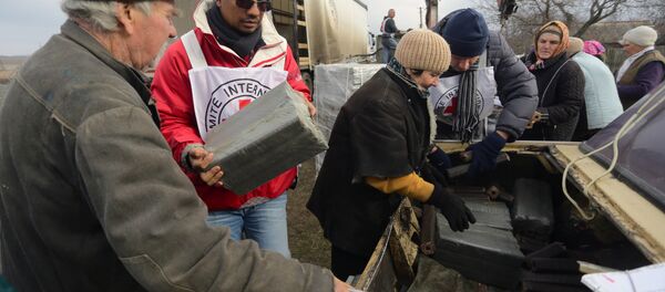 A picture taken on December 22, 2015 shows local residents receiving free wood briquettes delivered by the Red Cross in the village of Pischevik, in the Donetsk region A picture taken on December 22, 2015 shows local residents receiving free wood briquettes delivered by the Red Cross in the village of Pischevik, in the Donetsk region - Sputnik International