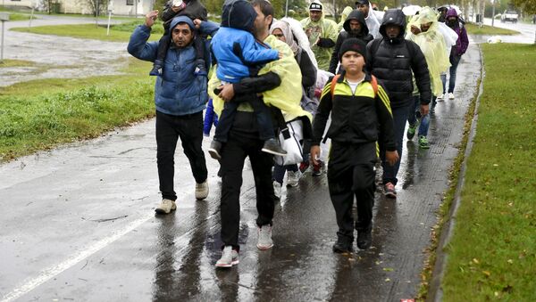 Refugees walk through the pouring rain from a public transport centre to the Lappia-building refugee reception centre in Tornio, northwestern Finland, on September 2015 - Sputnik International