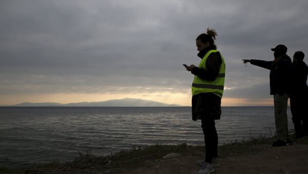 Volunteers wait for the arrival of a rubber dinghy packed with refugees and migrants on a beach on the Greek island of Lesbos, January 29, 2016. - Sputnik International