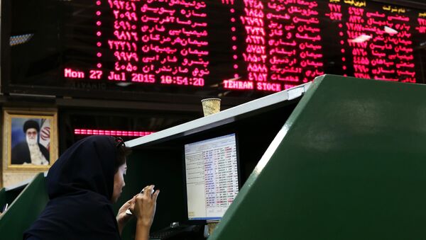 An Iranian dealer checks her mobile phone next to stock market activity boards at the stock exchange in the capital Tehran - Sputnik International