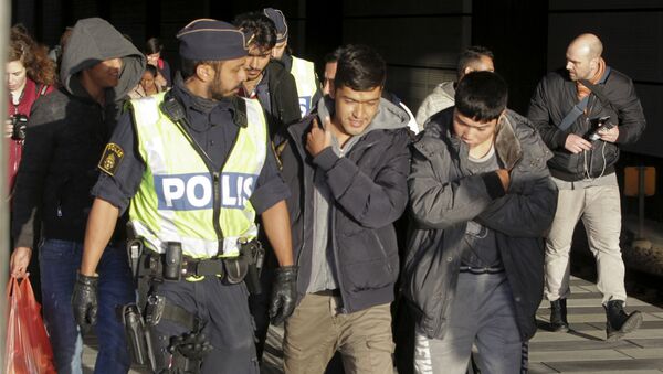 A group of migrants off an incoming train walk down a platform as they are accompanied by the police at the Swedish end of the bridge between Sweden and Denmark near Malmoe on November 12, 2015 - Sputnik International