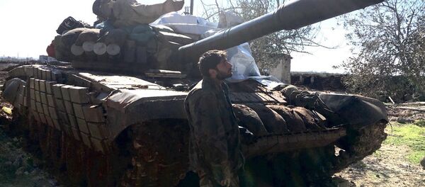 Syrian Arab Army soldier stands near a T72 tank in the town of Al-Shaykh Maskin in the Daraa province liberated from terrorists - Sputnik International