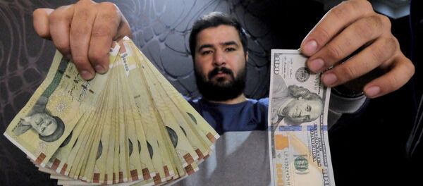 A money changer poses for the camera with a US dollar (R) and the amount being given when converting it into Iranian rials (L), at a currency exchange shop in Tehran's business district, Iran, in this January 20, 2016 file photo - Sputnik International