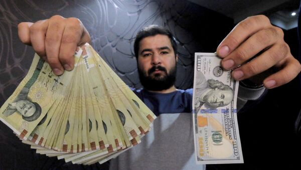 A money changer poses for the camera with a US dollar (R) and the amount being given when converting it into Iranian rials (L), at a currency exchange shop in Tehran's business district, Iran, in this January 20, 2016 file photo - Sputnik International