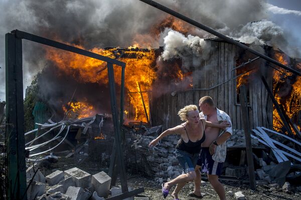 Local residents escape from a fire in the house destroyed in the Ukrainian armed forces' air attack on the village of Luganskaya Local residents escape from a fire in the house destroyed in the Ukrainian armed forces' air attack on the village of Luganskaya - Sputnik International