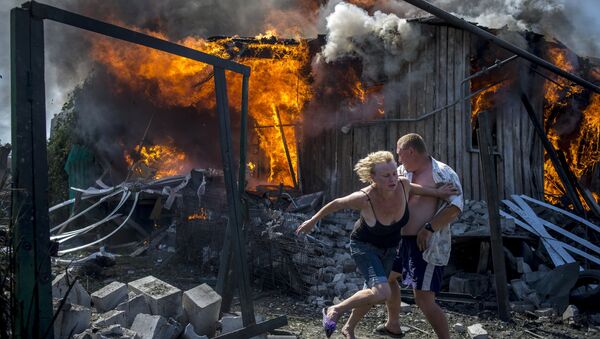 Local residents escape from a fire in the house destroyed in the Ukrainian armed forces' air attack on the village of Luganskaya - Sputnik International