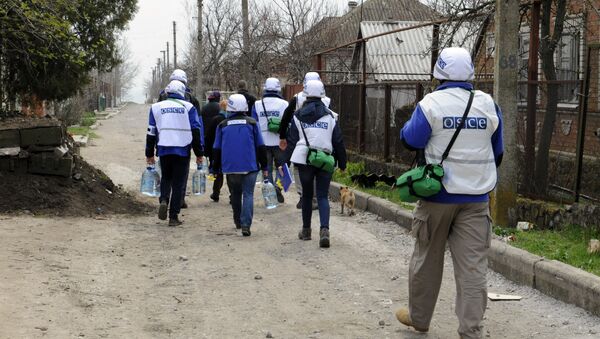 Monitors of the OSCE Special Monitoring Mission to Ukraine in Shirokine village, walk along a path on April 14, 2015 on the outskirts of the strategic port city of Mariupol - Sputnik International