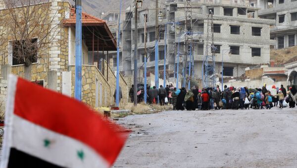 A Syrian national flag flutters on a barricade erected at the entrance of the besieged rebel-held Syrian town of Madaya as residents wait for a convoy of aid from the Syrian Arab Red Crescent on January 14, 2016 - Sputnik International