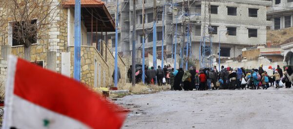 A Syrian national flag flutters on a barricade erected at the entrance of the besieged rebel-held Syrian town of Madaya as residents wait for a convoy of aid from the Syrian Arab Red Crescent on January 14, 2016 - Sputnik International