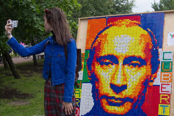 A girl takes a selfie against a portrait of Russian President Vladimir Putin composed of Rubik's Cubes at the festival of the social network VKontakte in St. Petersburg A girl takes a selfie against a portrait of Russian President Vladimir Putin composed of Rubik's Cubes at the festival of the social network VKontakte in St. Petersburg - Sputnik International