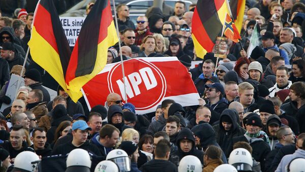 Supporters of anti-immigration right-wing movement PEGIDA (Patriotic Europeans Against the Islamisation of the West) hold up a banner with the logo of the far-right National Democratic Party (NPD) as they take part in in demonstration march, in reaction to mass assaults on women on New Year's Eve, in Cologne, Germany, January 9, 2016. - Sputnik International