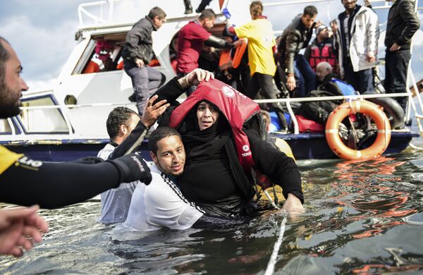 Migrant families - helped by rescuers - disembark on the Greek island of Lesbos after crossing with other migrants and refugees the Aegean Sea from Turkey, on November 25, 2015. Migrant families - helped by rescuers - disembark on the Greek island of Lesbos after crossing with other migrants and refugees the Aegean Sea from Turkey, on November 25, 2015. - Sputnik International