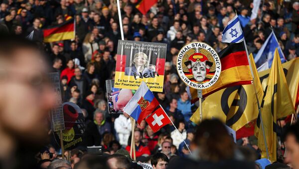 Supporters of the anti-Islam movement Patriotic Europeans Against the Islamisation of the West (PEGIDA) hold posters depicting German Chancellor Angela Merkel during a demonstration in Dresden, Germany - Sputnik International