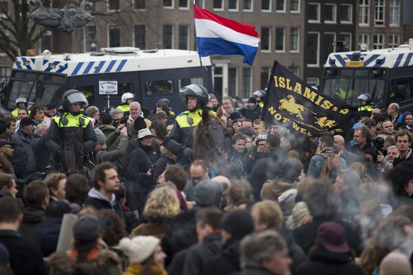 A flag reads Islamists Not Welcome as mounted Dutch riot police separates pro and anti Pegida demonstrators during a rally against islamisation in Amsterdam, Netherlands A flag reads Islamists Not Welcome as mounted Dutch riot police separates pro and anti Pegida demonstrators during a rally against islamisation in Amsterdam, Netherlands - Sputnik International