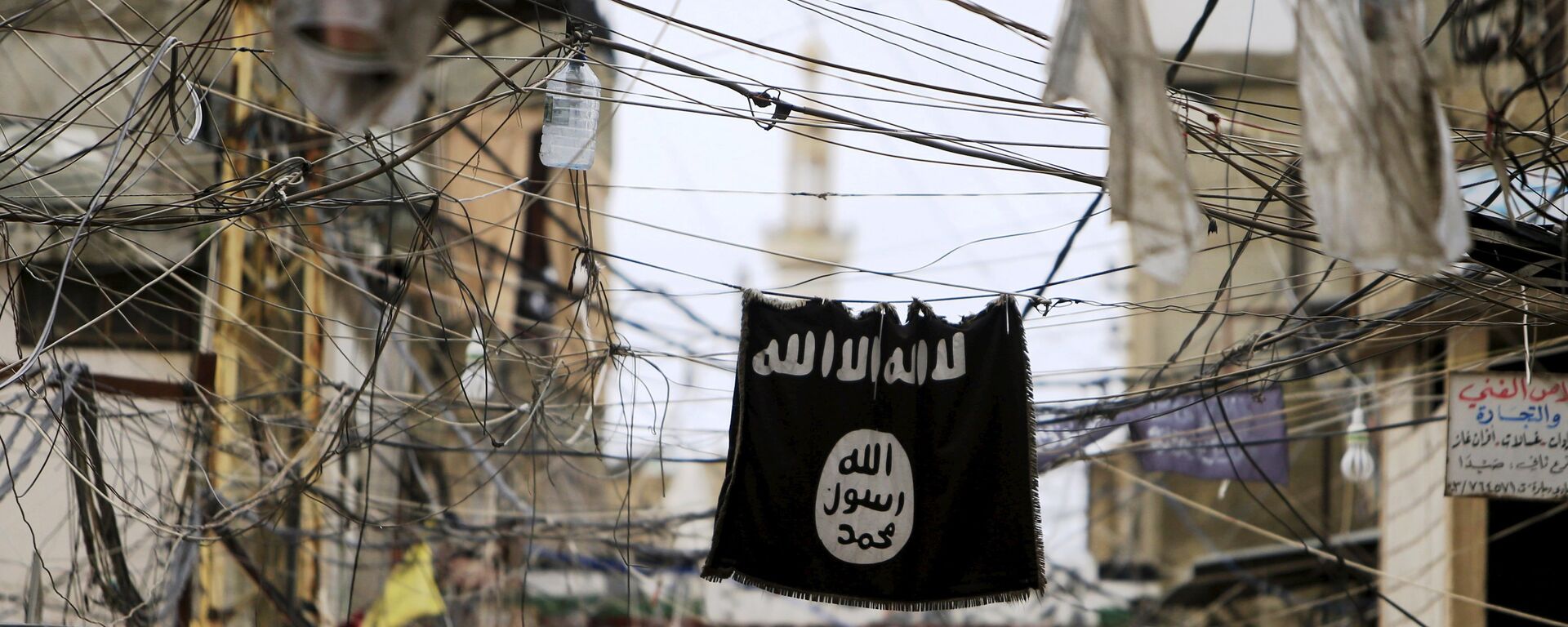 An Islamic State flag hangs amid electric wires over a street. - Sputnik International, 1920, 06.09.2021