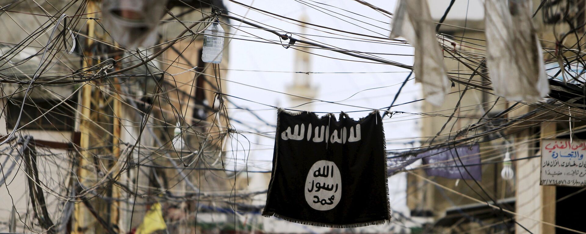 An Islamic State flag hangs amid electric wires over a street. - Sputnik International, 1920, 28.02.2021