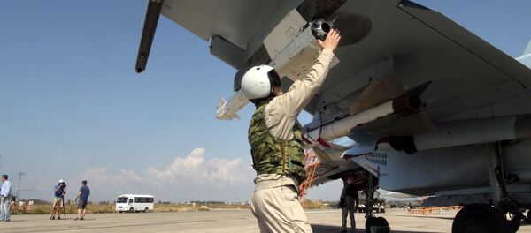 In this photo taken on Monday, Oct. 5, 2015, a Russian pilot fixes an air-to-air missile at his Su-30 jet fighter before a take off at Hmeimim airbase in Syria. - Sputnik International