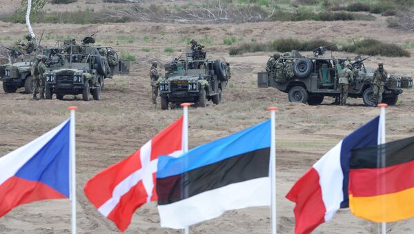 In this June 18, 2015,file photo flags wave in front of soldiers who take positions with their army vehicles during the NATO Noble Jump exercise on a training range near Swietoszow Zagan, Poland - Sputnik International