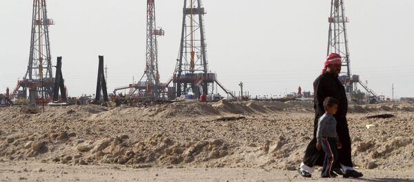 Iraqi people walk past the Rumaila oilfield in Basra, Iraq, January 26, 2016 Iraqi people walk past the Rumaila oilfield in Basra, Iraq, January 26, 2016 - Sputnik International