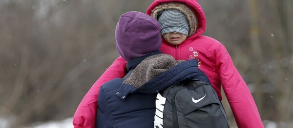 A migrant carries a child as they walk through a frozen field after crossing the border from Macedonia, near the village of Miratovac, Serbia, January 18, 2016. - Sputnik International