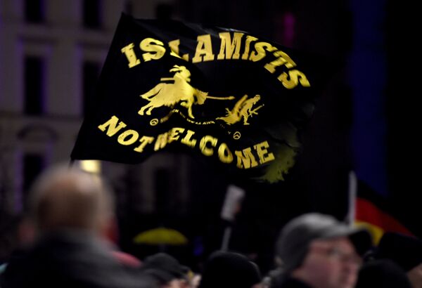 A flag reading Islamists not welcome flies among protestors from the PEGIDA movement (Patriotic Europeans Against the Islamisation of the Occident) attend a rally in Leipzig on January 11, 2016 A flag reading Islamists not welcome flies among protestors from the PEGIDA movement (Patriotic Europeans Against the Islamisation of the Occident) attend a rally in Leipzig on January 11, 2016 - Sputnik International