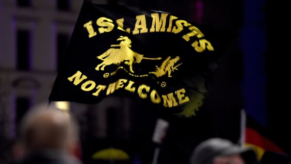 A flag reading Islamists not welcome flies among protestors from the PEGIDA movement (Patriotic Europeans Against the Islamisation of the Occident) attend a rally in Leipzig on January 11, 2016 - Sputnik International
