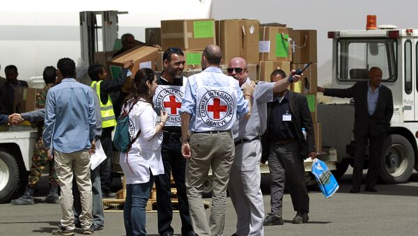 Workers from the International Committee of the Red Cross (ICRC) stand on the tarmac as emergency medical aid from the ICRC is offloaded off a plane following its arrival at the international airport in Sanaa on April 10, 2015 - Sputnik International