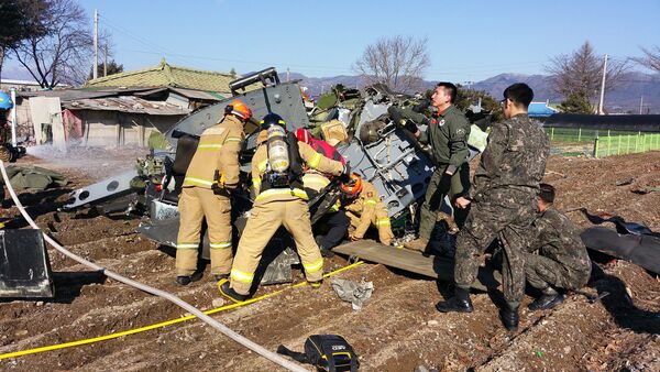Rescue personnel stand before a crashed UH-1H military helicopter in a field in Chuncheon, in South Korea's eastern Gangwon province, on February 15, 2016. - Sputnik International