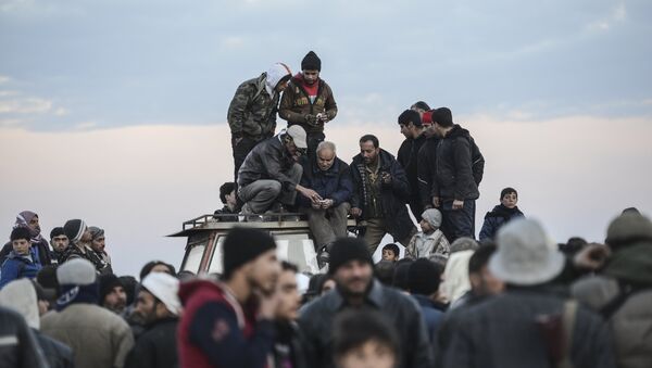 Men stand on a roof of a vehicle as Syrians fleeing the northern embattled city of Aleppo wait on February 5, 2016 in Bab-Al Salama, next to the city of Azaz, northern Syria, near Turkish crossing gate. - Sputnik International