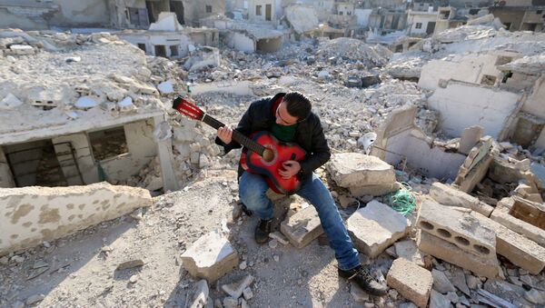 Shehab, a 23-year-old Syrian, practices the guitar amidst the rubble of buildings in the northern Syrian city of Aleppo on December 11, 2015. - Sputnik International