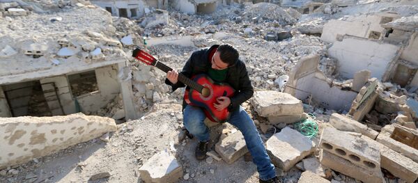 Shehab, a 23-year-old Syrian, practices the guitar amidst the rubble of buildings in the northern Syrian city of Aleppo on December 11, 2015. Shehab, a 23-year-old Syrian, practices the guitar amidst the rubble of buildings in the northern Syrian city of Aleppo on December 11, 2015. - Sputnik International