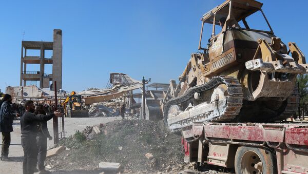 A bulldozer is unloaded from a truck as people gather around the rubble of a hospital supported by Doctors Without Borders (MSF) near Maaret al-Numan, in Syria's northern province of Idlib, on February 15, 2016 - Sputnik International