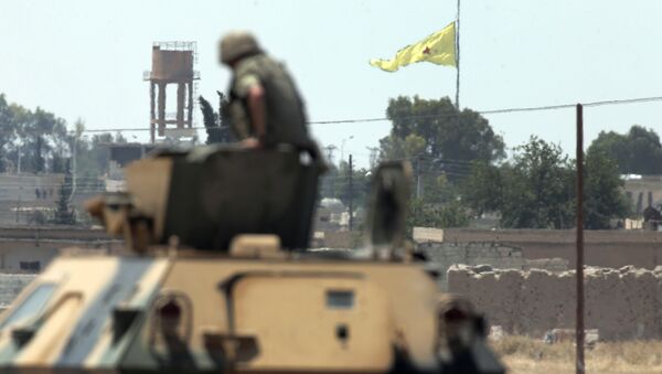 In this photo taken from the Turkish side of the border between Turkey and Syria, in Akcakale, southeastern Turkey, a Turkish soldier on an armoured personnel carrier watches as in the background a flag of the Kurdish People's Protection Units, or YPG, is raised over the city of Tal Abyad, Syria, Tuesday, June 16, 2015 - Sputnik International