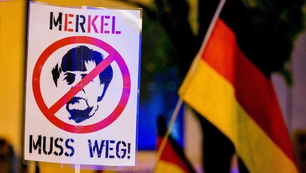 A participant of a rally of the Pegida movement (Patriotische Europaeer gegen die Islamisierung des Abendlandes, which translates to Patriotic Europeans Against the Islamisation of the Occident) holds a sign depicting German chancellor Angela Merkel and reading Merkel must go (Merkel muss weg) in Munich, southern Germany, on November 9, 2015 - Sputnik International