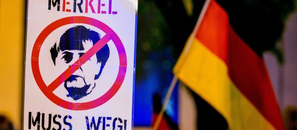 A participant of a rally of the Pegida movement (Patriotische Europaeer gegen die Islamisierung des Abendlandes, which translates to Patriotic Europeans Against the Islamisation of the Occident) holds a sign depicting German chancellor Angela Merkel and reading Merkel must go (Merkel muss weg) in Munich, southern Germany, on November 9, 2015 A participant of a rally of the Pegida movement (Patriotische Europaeer gegen die Islamisierung des Abendlandes, which translates to Patriotic Europeans Against the Islamisation of the Occident) holds a sign depicting German chancellor Angela Merkel and reading Merkel must go (Merkel muss weg) in Munich, southern Germany, on November 9, 2015 - Sputnik International