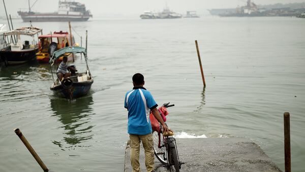 A local resident waits for a boat to cross the island during a thick blanket of haze over Port Klang on October 20, 2015 - Sputnik International