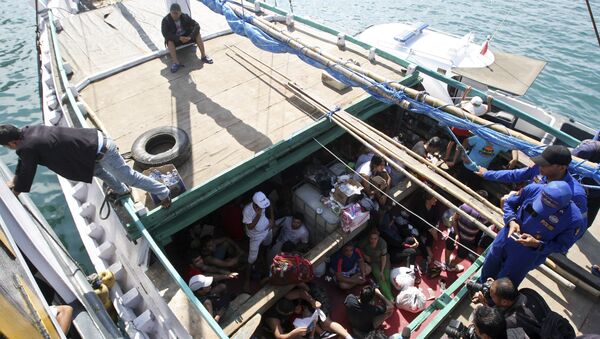 In this May 12, 2013 file photo, Iranian asylum seekers who were caught in Indonesian waters while sailing to Australia, sit on a boat, at Benoa port in Bali, Indonesia - Sputnik International