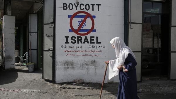 A Palestinian woman walks past a mural calling people to boycott Israeli goods in the al-Azzeh refugee camp near the West Bank city of Bethlehem on September 17, 2014 - Sputnik International