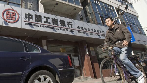 A man rides past a branch of the Industrial and Commercial Bank of China in the border city of Dandong in northeast China - Sputnik International