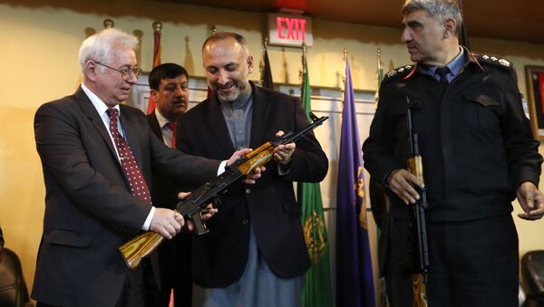 Russian Federation Ambassador, Alexander Mantytskiy, left, hands over an AK-47 to Afghan National Security Advisor, Mohammad Hanif Atmar, center, as the symbol of his country's military donation to the Afghan government, at Kabul International Airport, Wednesday, Feb. 24, 2016. - Sputnik International