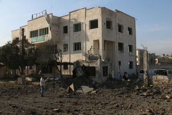 Syrians stand outside a damaged charity clinic for women and children following reported air strikes in the city of Azaz, on Syria's northern border with Turkey, on February 15, 2016. Syrians stand outside a damaged charity clinic for women and children following reported air strikes in the city of Azaz, on Syria's northern border with Turkey, on February 15, 2016. - Sputnik International