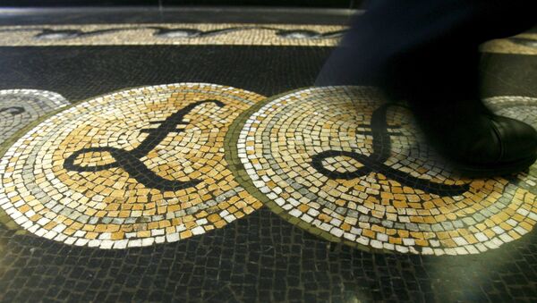 An employee is seen walking over a mosaic of pound sterling symbols set in the floor of the front hall of the Bank of England in London, in this March 25, 2008 file photograph. - Sputnik International